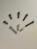 Seven dark metallic threaded hardware components arranged in a loose circle on a plain off-white surface. Size 2 stitching Pins, Steel and Aluminum. 