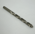 A single metal drill bit with a twisted flute design, photographed diagonally on a textured white fabric background.