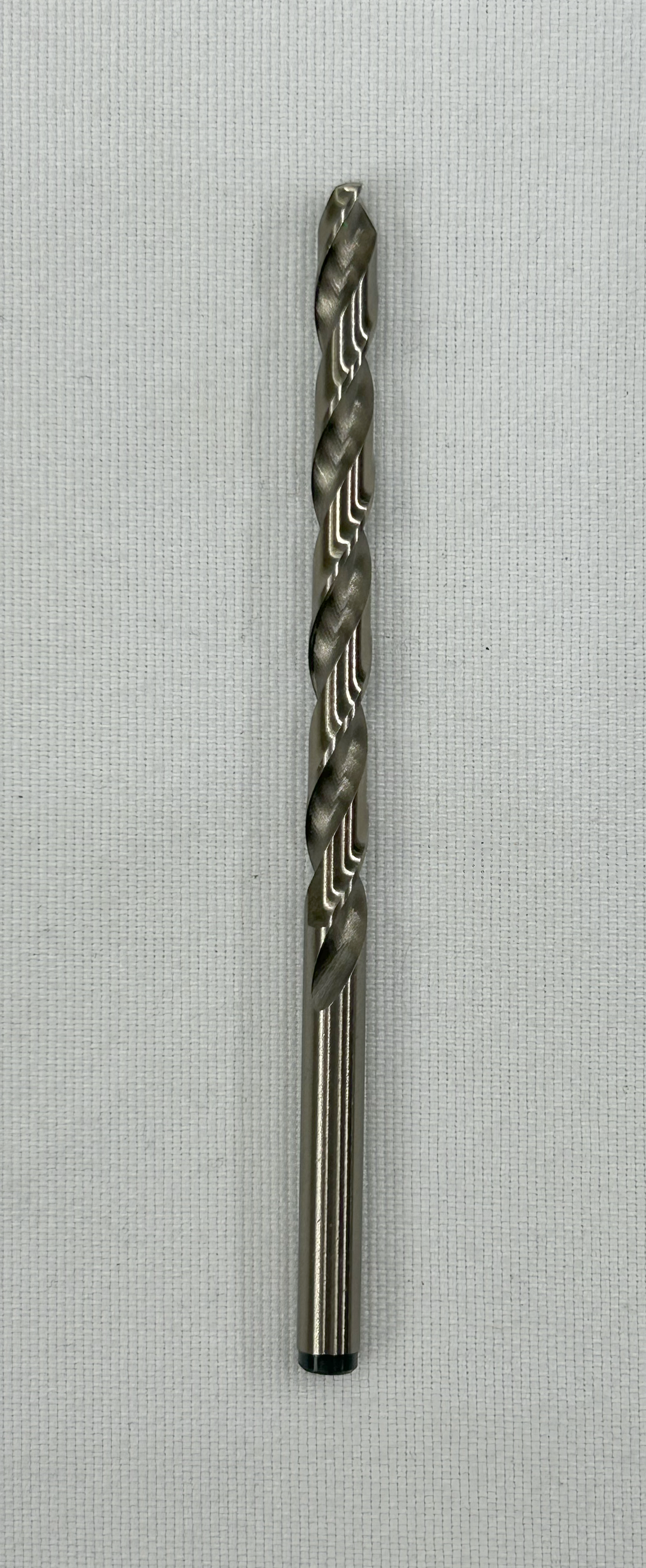 A single metal drill bit, wire size 7, with a twisted flute design, shown vertically against a light gray textured background.