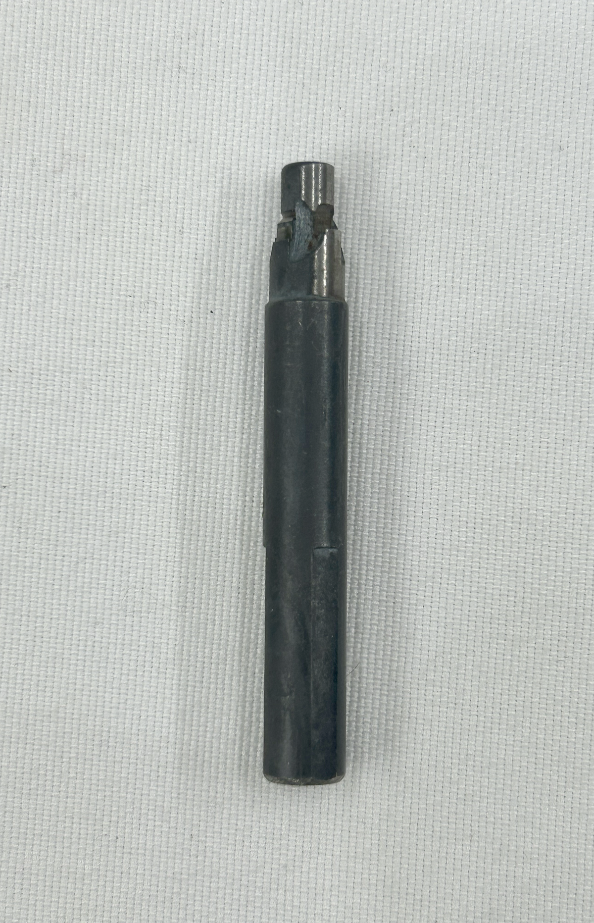 A black metal socket wrench bit with a slotted center, shown vertically on a textured white background.