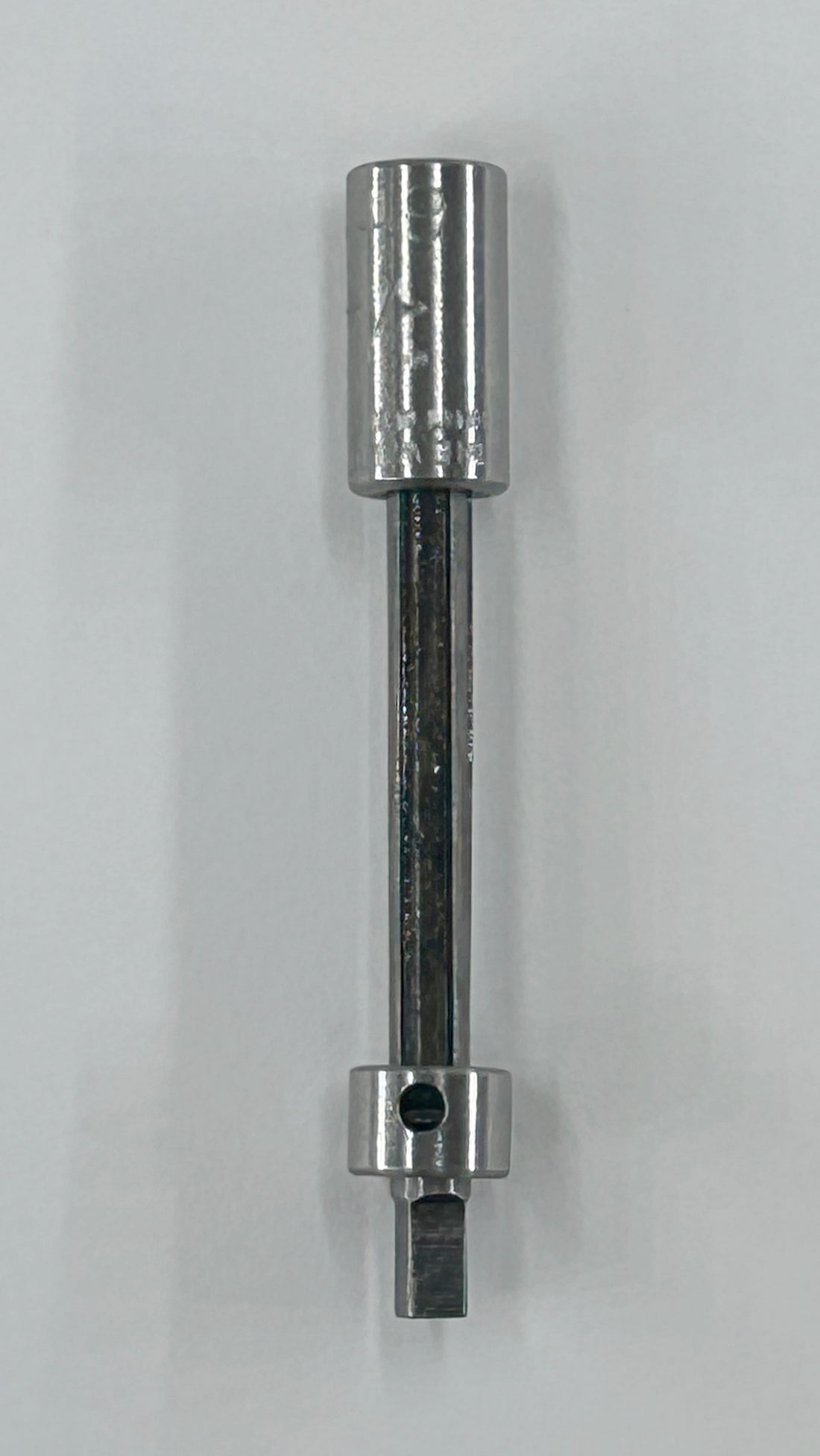 A metallic socket extension bar tool with a polished silver finish, shown vertically against a plain light gray background.