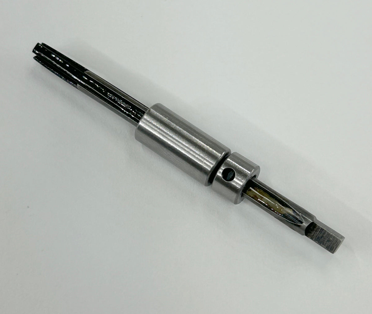 A metal cylindrical tool bit component with a silver body, black fluted shank, and exposed cutting edges, photographed on a plain light background.
