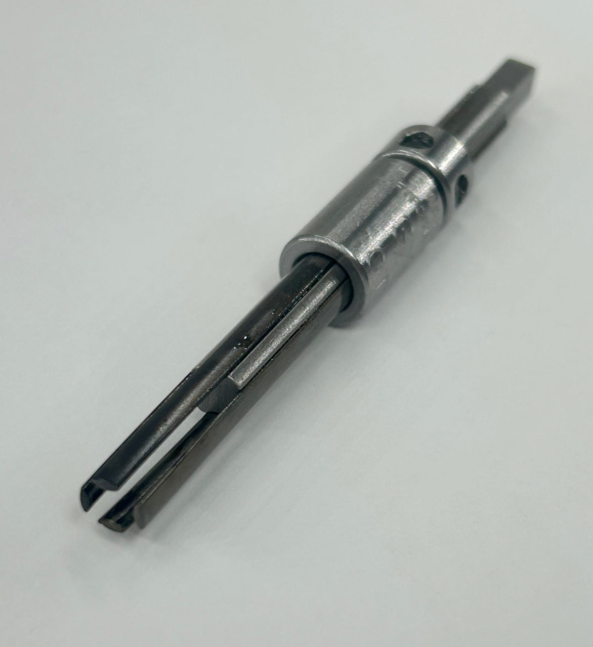 A metal mechanical tool or hardware component with a silver cylindrical body and dark gray forked ends, photographed on a plain light background.